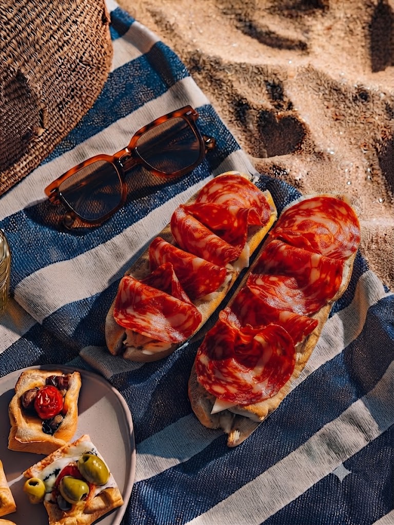 Dos bocadillos de chorizo sobre una toalla de playa.