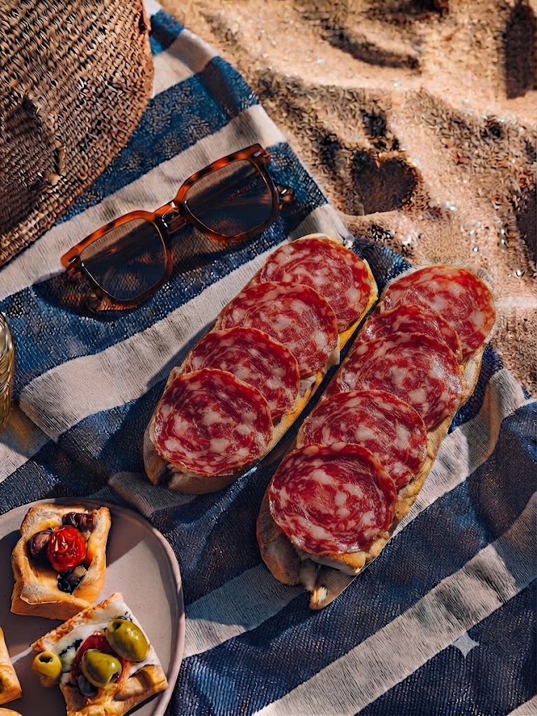 Dos bocadillos de salchichón sobre una toalla de playa.
